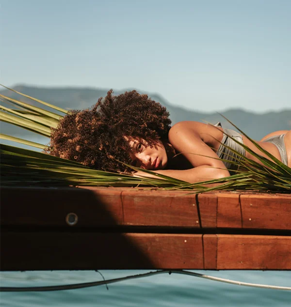 Woman laying down in palms next to a pool